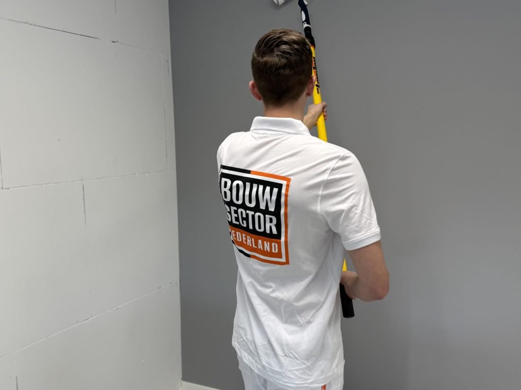 Schilder saust een grijze muur naast een wand van onbehandelde bouwblokken