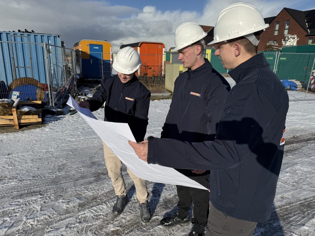 Drie vakmensen van Bouwsector Nederland bespreken buiten een bouwtekening